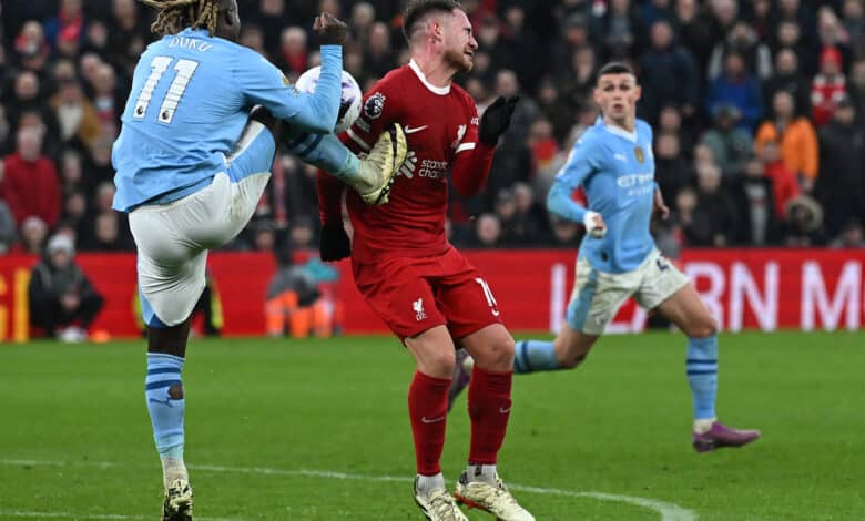 Manchester City's Belgian midfielder #11 Jeremy Doku (L) kicks Liverpool's Argentinian midfielder #10 Alexis Mac Allister during the English Premier League football match between Liverpool and Manchester City at Anfield in Liverpool, north west England on March 10, 2024