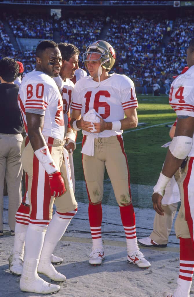 San Diego - Nov 1988: QB # 16 Joe Montana, WR # 80 Jerry Rice, C # 51 Randy Cross conversing on the sidelines. San Francisco 49ers 48 vs San Diego Chargers 10 at Jack Murphy Stadium in San Diego, California.