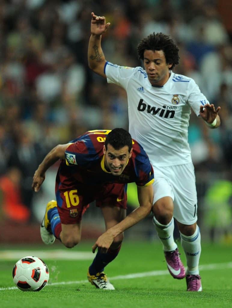 MADRID, SPAIN - APRIL 16:  Sergio Busquets (L) of Barcelona is tackled by Marcelo  of Real Madrid during the La Liga match between Real Madrid and Barcelona at Estadio Santiago Bernabeu on April 16, 2011 in Madrid, Spain.  