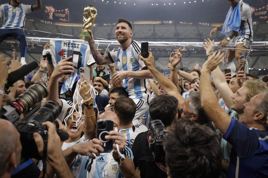 Football Calendar 101 - Lionel Messi of Argentina shows off the FIFA World Cup Trophy to fans while he is carried around the pitch on the shoulders of former teammate Sergio Aguero after the team's victory during the FIFA World Cup Qatar 2022 Final match between Argentina and France at Lusail Stadium on December 18, 2022 in Lusail City, Qatar.