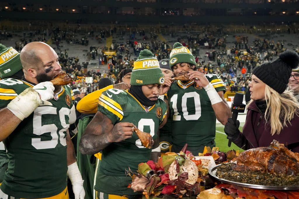 GREEN BAY, WISCONSIN - NOVEMBER 28: Quarterback Jordan Love #10 of the Green Bay Packers, linebacker Isaiah McDuffie #58, and running back Josh Jacobs #8 enjoy Thanksgiving turkey with NBC Sports reporter Melissa Stark after an NFL football game against the Miami Dolphins, at Lambeau Field on November 28, 2024 in Green Bay, Wisconsin.
