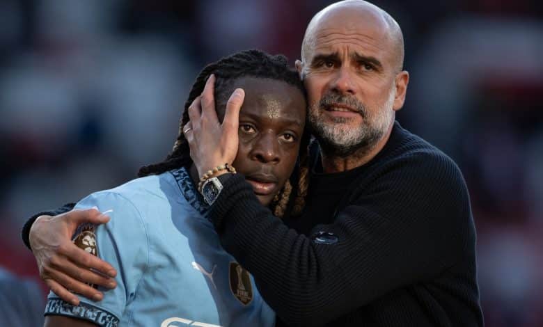 Jeremy Doku of Manchester City interacts with Pep Guardiola, Manager of Manchester City