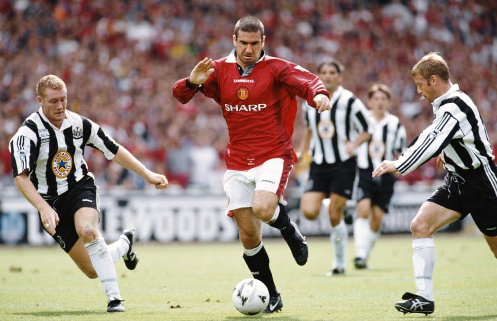 Manchester United player Eric Cantona (c) beats Steve Watson and David Batty (r) during the FA Charity Shield match between Manchester United and Newcastle United at Wembley Stadium on August 11, 1996 in London, England.