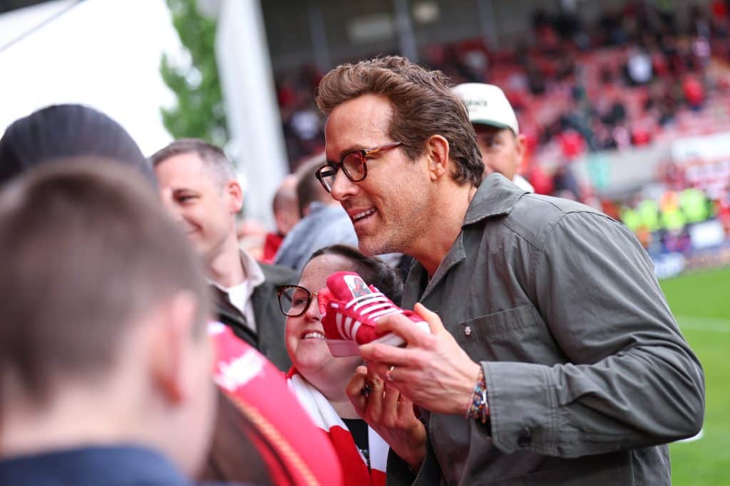 WREXHAM, WALES - APRIL 26: Ryan Reynolds co-owner of Wrexham poses with a Deadpool Adidas trainer ahead of the Sky Bet League One match between Wrexham AFC and Charlton Athletic FC at Racecourse Ground on April 26, 2025 in Wrexham, Wales. 