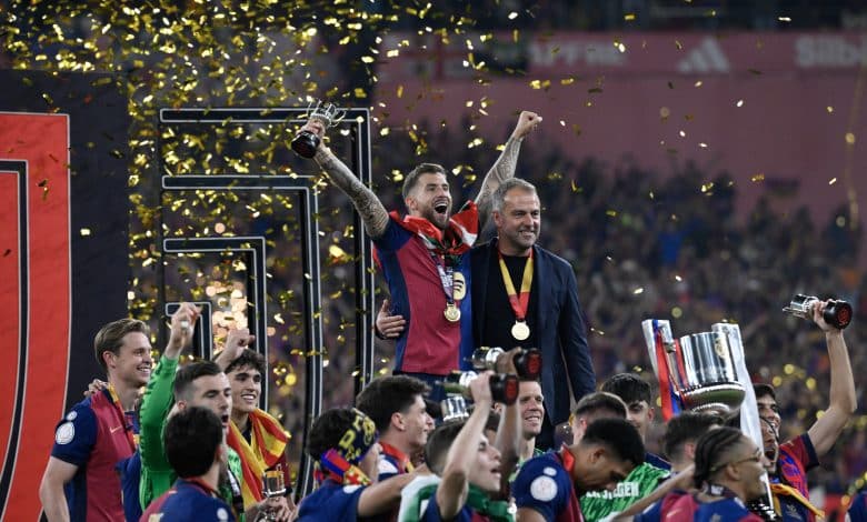 Barcelona's Spanish defender #05 Inigo Martinez Berridi (L) and Barcelona's German coach Hans-Dieter Flick (R) celebrate their victory with teammates after winning the Spanish Cup, Copa del Rey (King's Cup) final football match between FC Barcelona and Real Madrid CF at La Cartuja stadium in Seville on April 26, 2025.